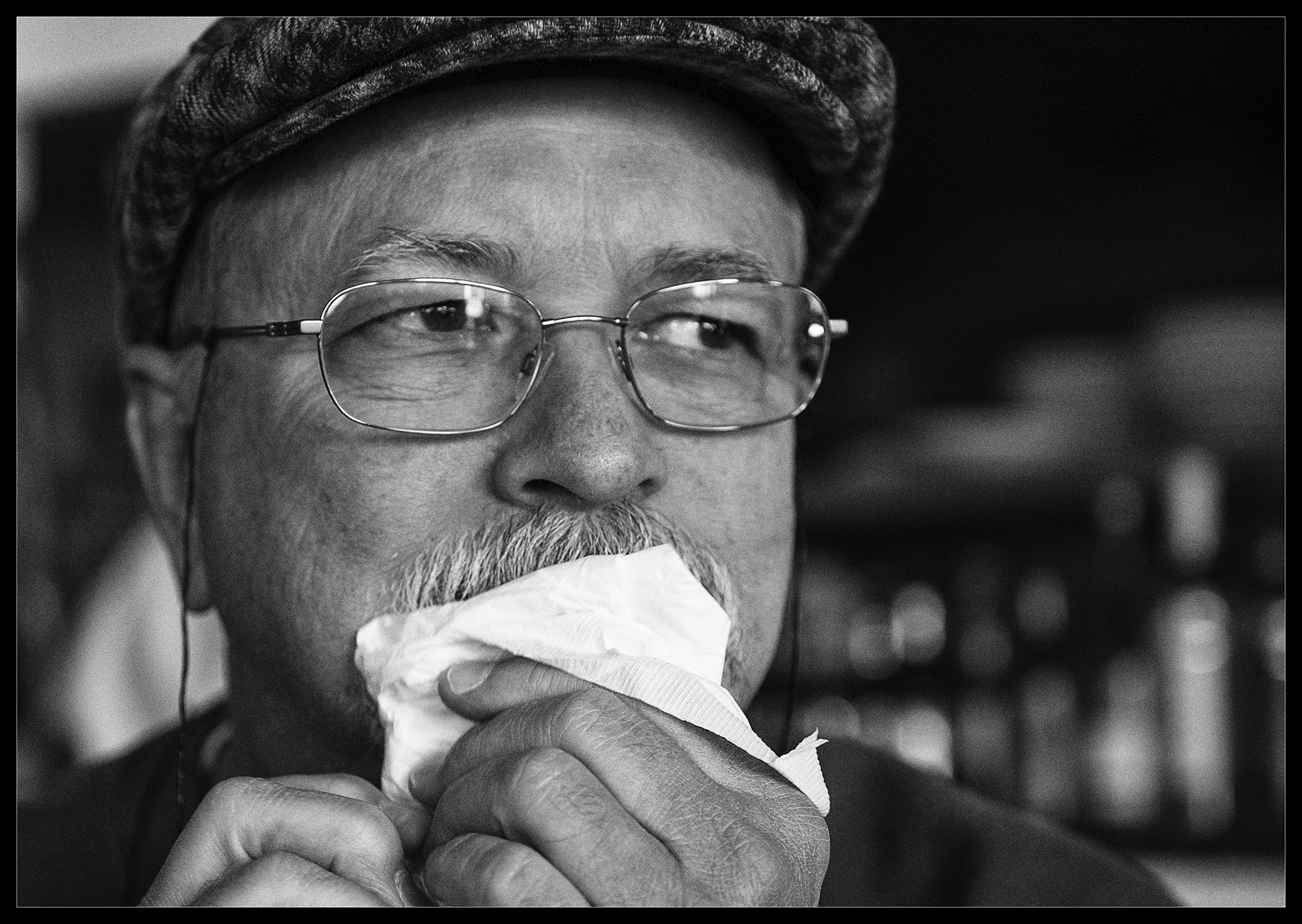 A photo of an older, well dressed gentleman with hat and glasses while eating.