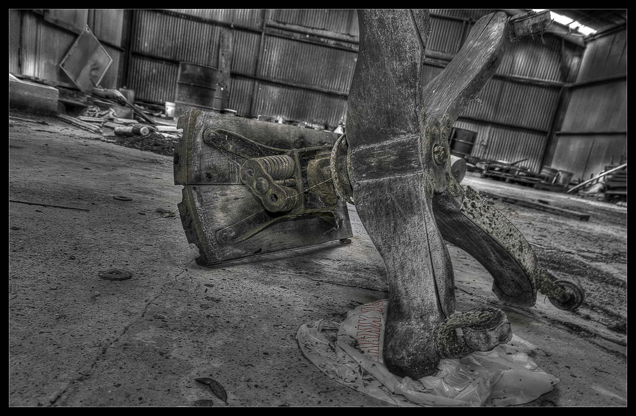 A broken stool with a plastic garbage bag amongst clutter and dirt.