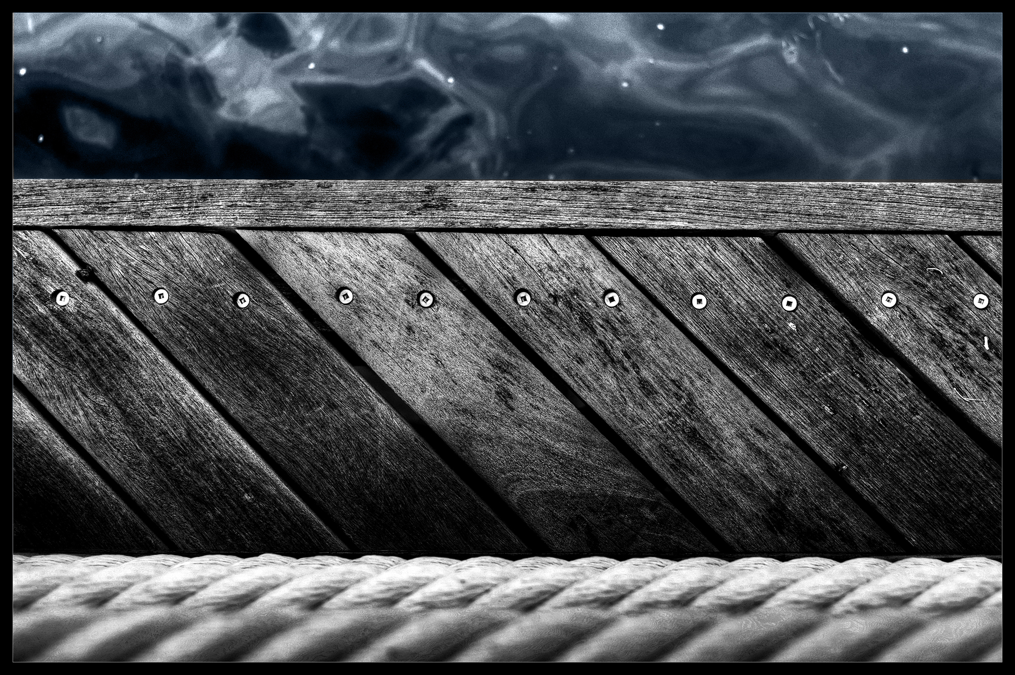 A selective color photo of wood textures and rope.